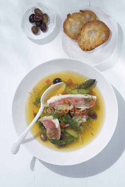 Rotbarbe mit grünem Spargel, Safran, kleinen Nizza-Oliven und geröstetem Brot (Südfrankreich) — Stockfoto