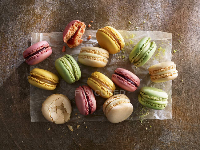 Macarons coloridos diferentes em papel contra um fundo de madeira — Fotografia de Stock