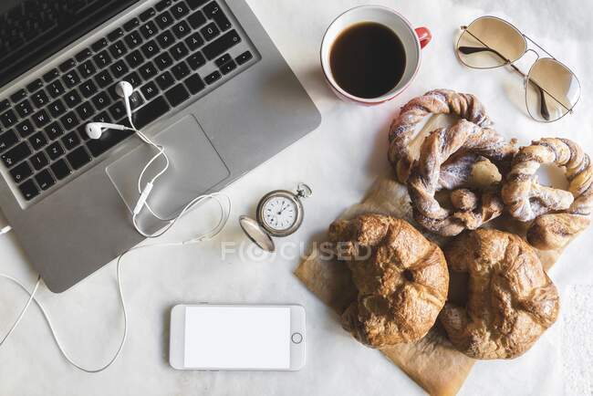 Petit déjeuner au bureau avec tasse de café et bretzels sucrés — Photo de stock