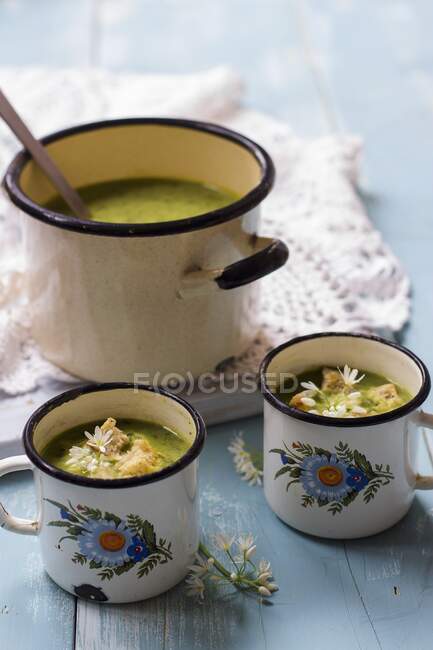Creamy wild garlic soup with croutons in enamel cups — Stock Photo