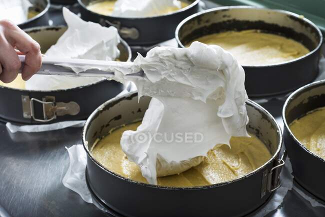 Brancos de ovo chicoteados sendo colocados em uma lata de bolo — Fotografia de Stock