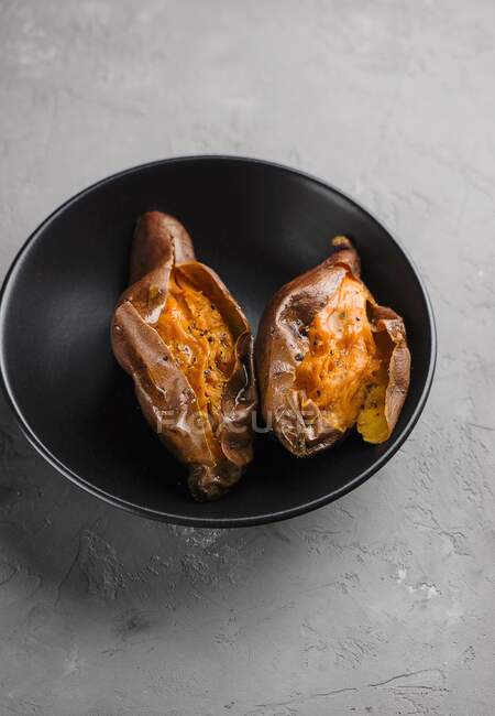 Oven baked sweet potatoes on black plate — Stock Photo