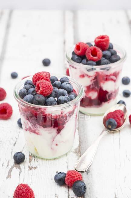 Postres de yogur griego con gelatina de frutas y frambuesas frescas y arándanos - foto de stock