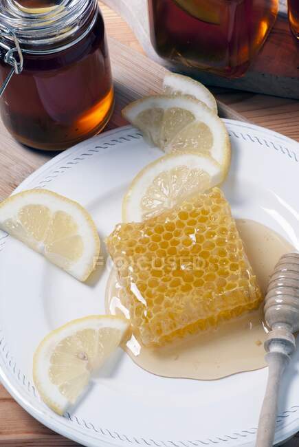 Honey comb on plate with lemons — Stock Photo