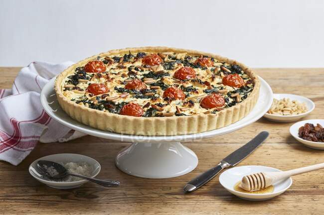 Spinach quiche with cherry tomatoes, raisins and pine nuts — Stock Photo
