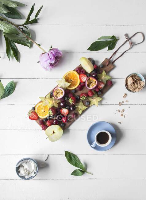 Various fresh fruits served on a wooden board and a cup of coffee — Stock Photo