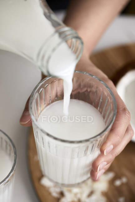 Verter leche de coco casera en el vaso - foto de stock