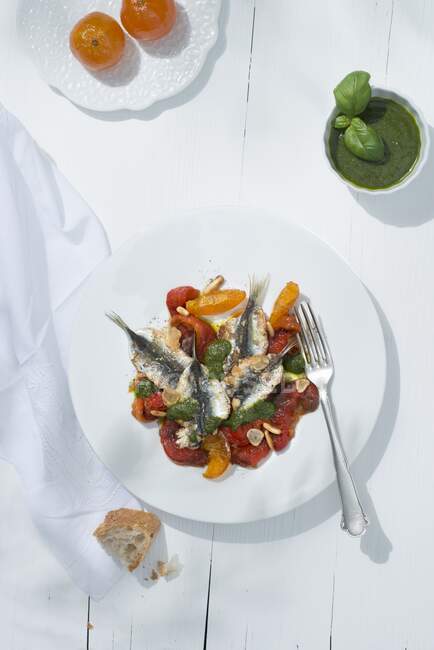 Filetes de sardinhas quentes com tomates e creme de manjericão no prato — Fotografia de Stock