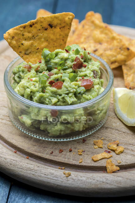 Various fresh ingredients placed on lumber table near pot with yummy guacamole — Stock Photo