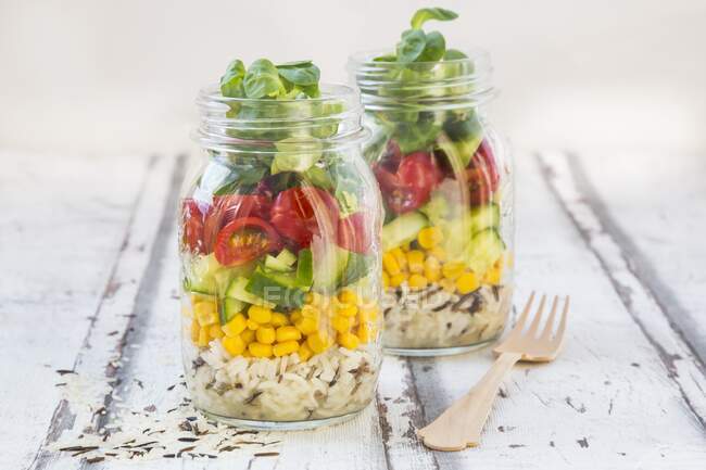 Reissalat im Glas mit Wildreis, Zuckermais, Gurken, Tomaten und Feldsalat — Stockfoto