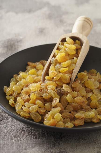 Raisins with a wooden scoop in a bowl — Stock Photo