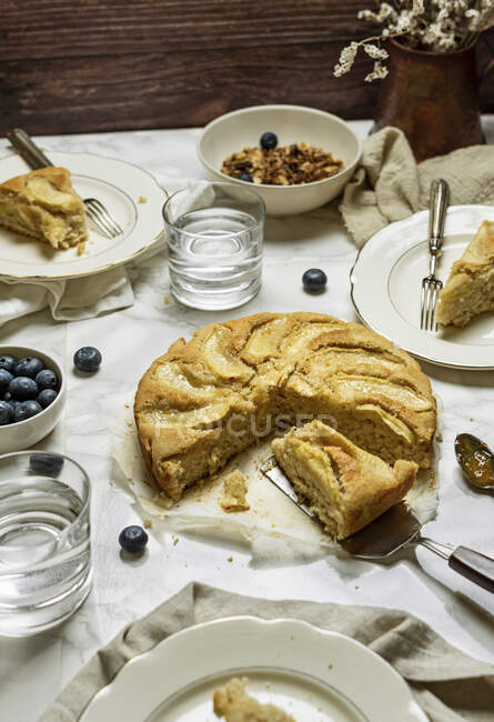 Стол для завтрака с безглютеновым веганским тортом, голубыми ягодами и мюсли — стоковое фото