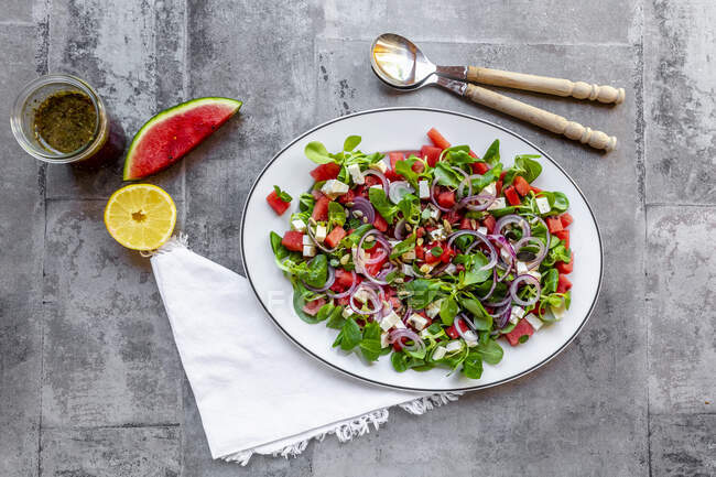 Салат з кавуна з листям баранини, фетою, червоною цибулею та м'ятою — стокове фото