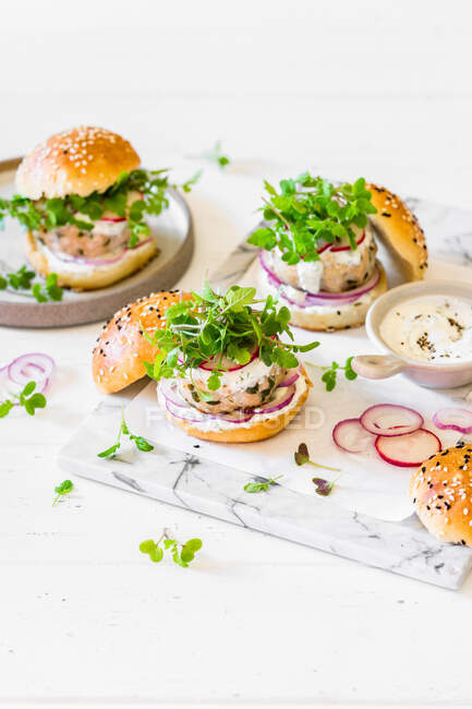 Chicken patty burgers with red onion, radish, microgreen mustard and yoghurt sauce — Stock Photo
