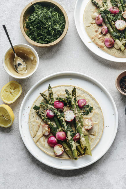 Chickpea pancakes with asparagus roasted radish topped with tahini sauce — Stock Photo