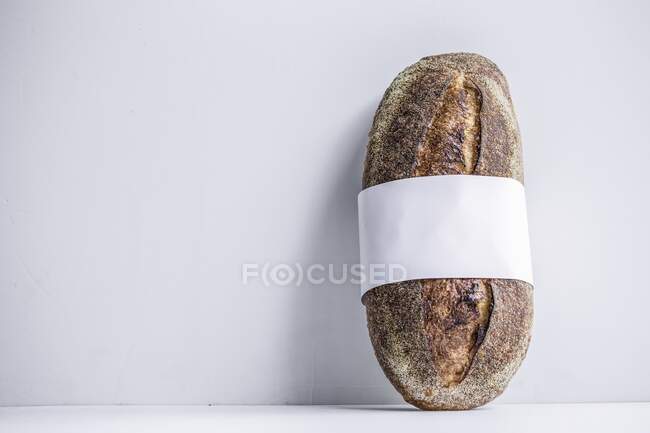 A loaf of sourdough bread wrapped with a white bow — Stock Photo