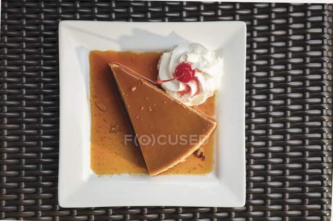 A triangle piece of flan with whipped cream and a cherry — Stock Photo