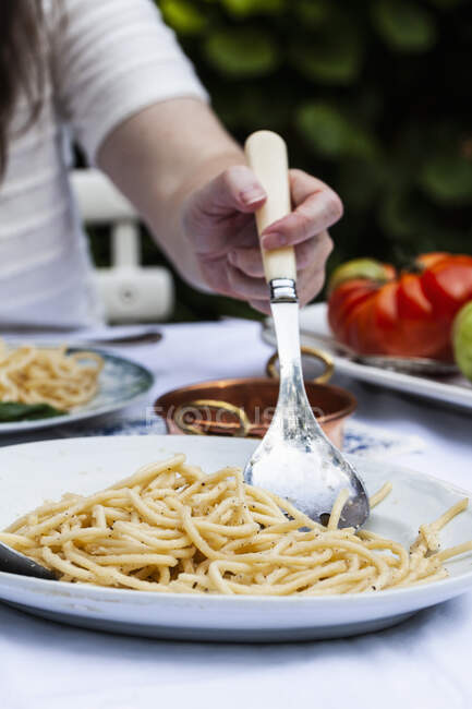 Um prato de macarrão cácio e pepe sendo servido, macarrão com queijo e pimenta na mesa ao ar livre — Fotografia de Stock
