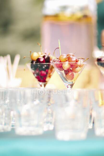 Óculos com cerejas diferentes em uma mesa de jardim — Fotografia de Stock