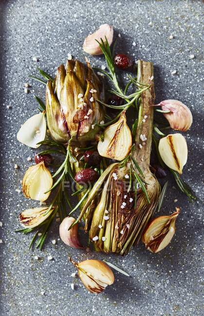 Oven-roasted artichokes with garlic, onions, olives and rosemary — Stock Photo