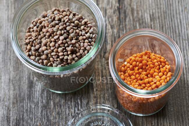 Brown and red lentils in glass jars — Stock Photo