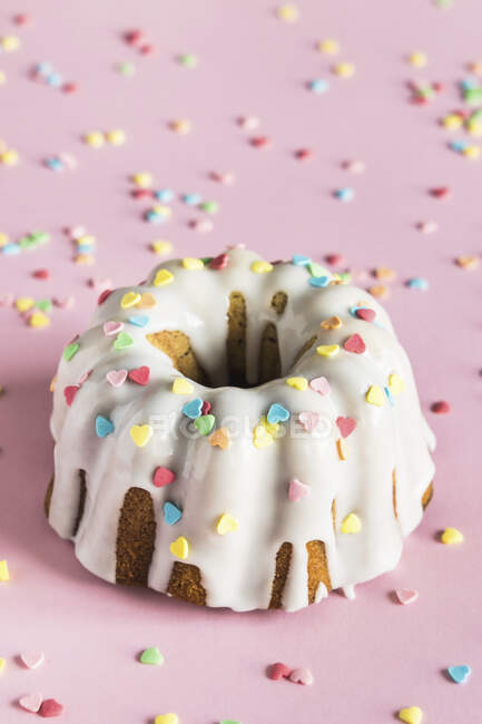 Gâteau Bundt avec glaçure blanche et saupoudres de sucre en forme de coeur coloré pour la Saint-Valentin — Photo de stock