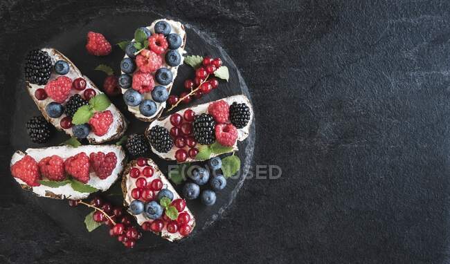 Bruschettas with berries and cream cheese on plate — Stock Photo