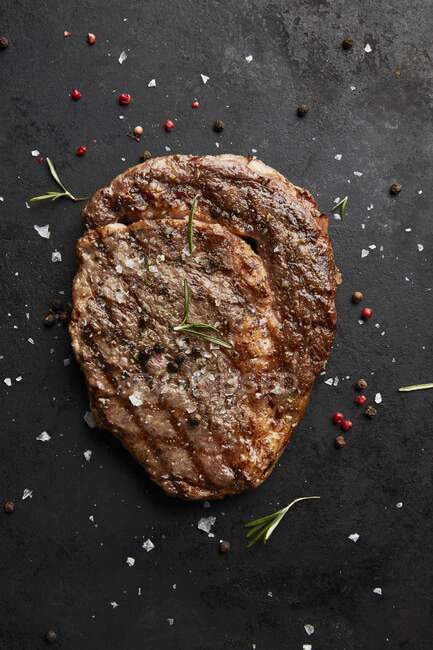 Un steak de bœuf grillé aux épices sur fond noir (vue du dessus) — Photo de stock