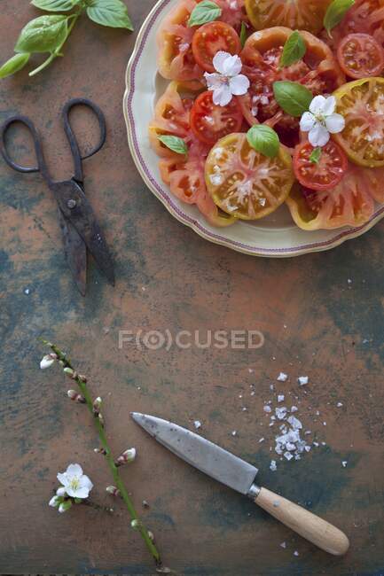Salada de tomate com flocos de sal marinho, manjericão e flores — Fotografia de Stock