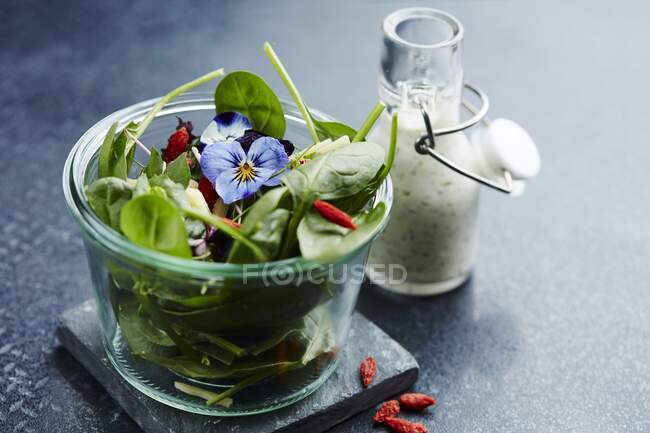 Spinach salad with goji berries, pansies, and yogurt dressing — Stock Photo