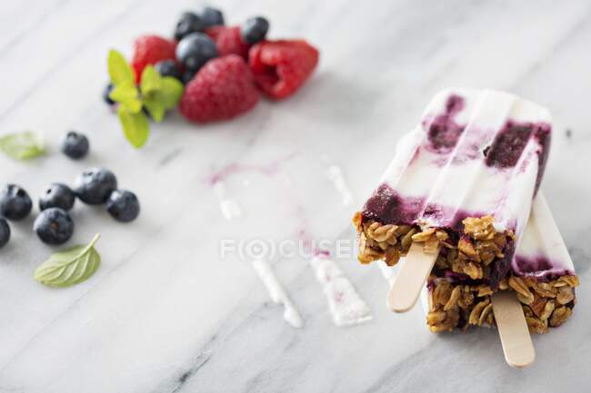 Yogurt, berry and granola breakfast popsicles on marble surface — Stock Photo