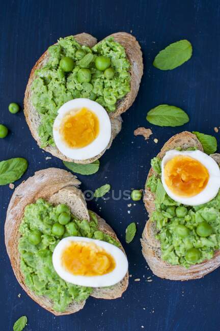 Toasts with mashed green peas, boiled egg and fresh basil — Stock Photo