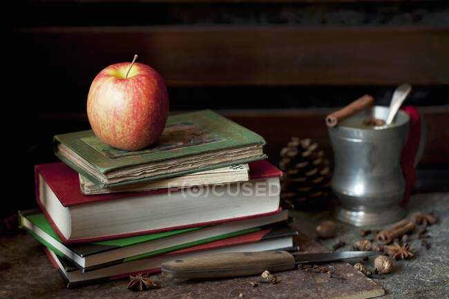 Una mela Pink Lady su un mucchio di vecchi libri con succo di mela rimuginato — Foto stock