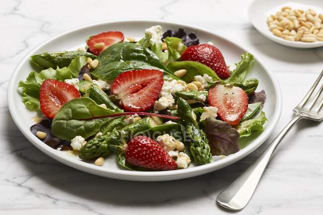 Green asparagus with a mixed leaf salad, strawberries and sheep cheese — Stock Photo