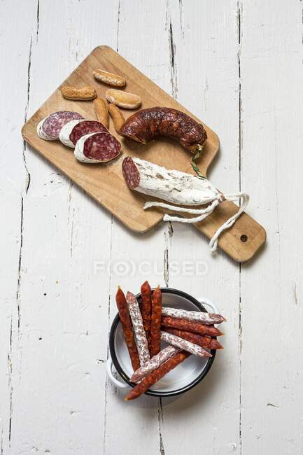 Various Spanish sausages in an enamel dish and on a wooden board (top view) — Stock Photo