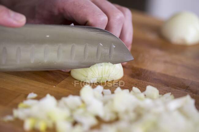 Picar cebollas con un cuchillo Santoku - foto de stock