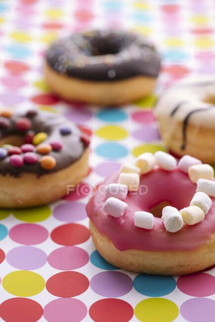 Bunt dekorierte Donuts auf einer gepunkteten Tischdecke — Stockfoto