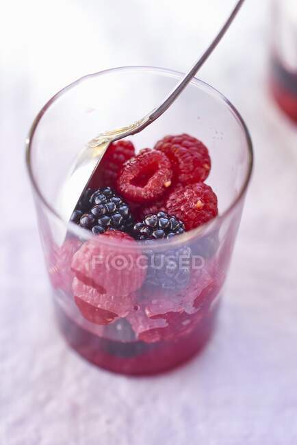 Fresh raspberries and blackberries in glass with spoon — Stock Photo
