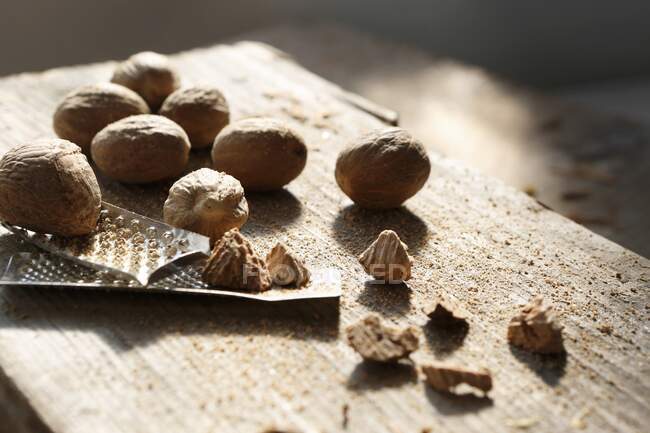Whole and grated nutmegs and a nutmeg grater — Stock Photo
