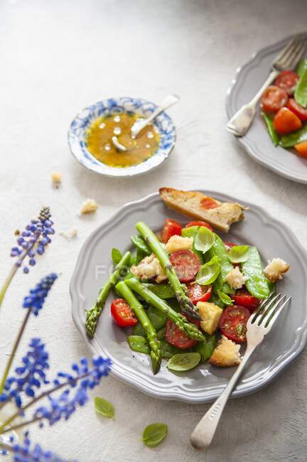 Весенний салат с зеленой спаржей, помидорами, базиликом и фокаччей — стоковое фото