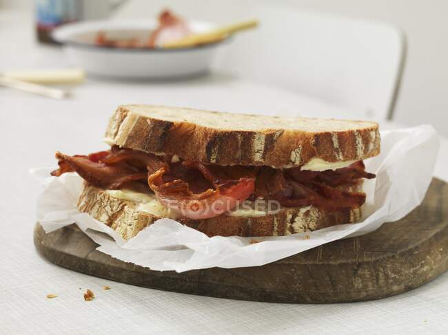 Sandwich with cheese and crispy bacon on wooden board — Stock Photo