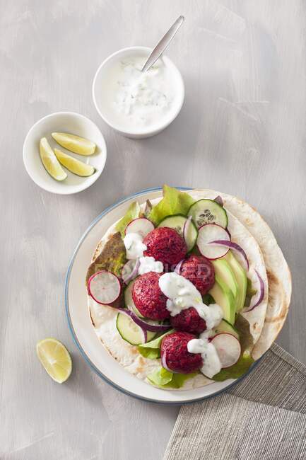 Tortilla with beet falafel, avocado, radish, cucumber and yogurt dressing — Stock Photo