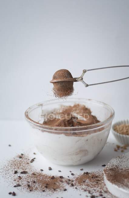 Peneirando cacau em pó em uma mistura de merengue de chocolate — Fotografia de Stock