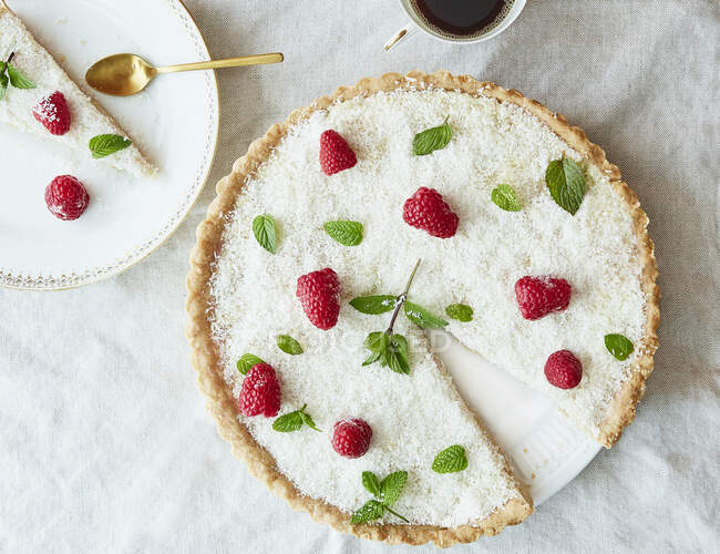 Cake with coconut sprinkles, raspberries and mint leaves — Stock Photo