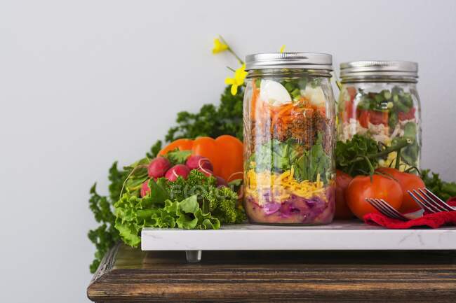 Two layered salads in glass jars with spinach, beans, cheese and eggs — Stock Photo