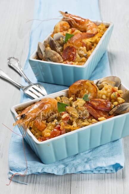 Portions of paella with prawns and chorizo with forks — Stock Photo