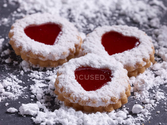 Three Linz cookies surrounded by powdered sugar — Stock Photo