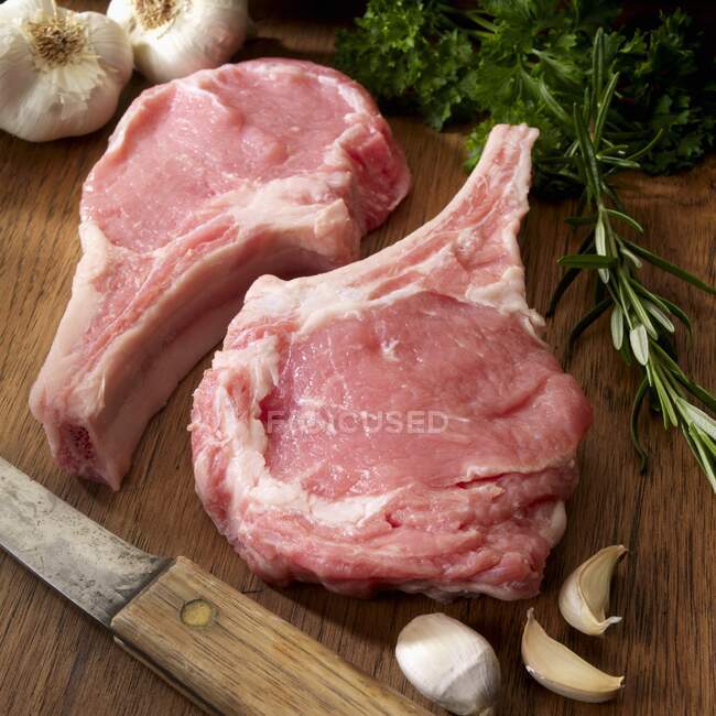 Two raw Veal Chops with herbs and garlic on cutting board — Stock Photo