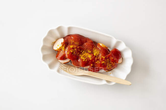Salchicha al curry en un plato de porcelana - foto de stock