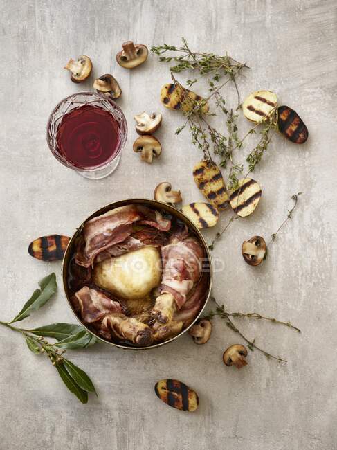 Coq au Vin with grilled potato halves, mushrooms, thyme, and a glass of red wine — Stock Photo